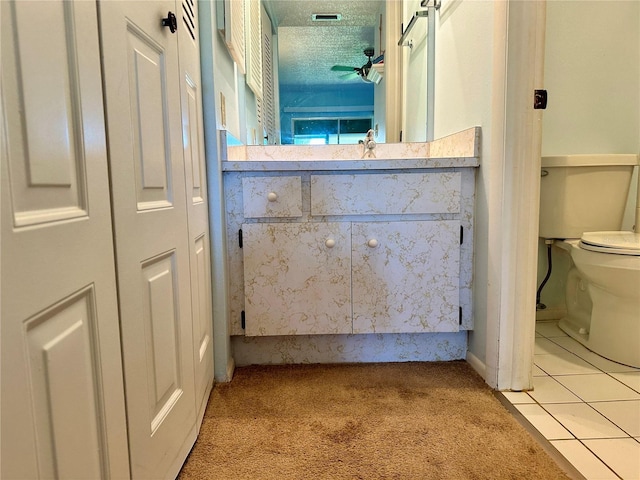 bathroom with tile patterned flooring, vanity, toilet, and a textured ceiling