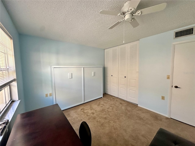 unfurnished bedroom featuring light carpet, a textured ceiling, and ceiling fan