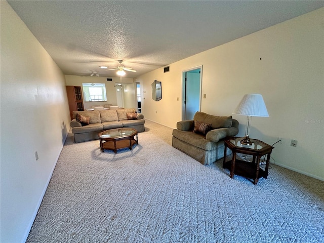 living room with carpet, ceiling fan, and a textured ceiling