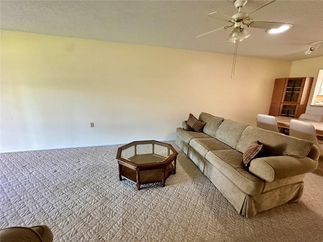 living room with ceiling fan, carpet floors, and a textured ceiling