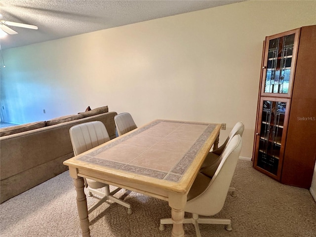 dining room with ceiling fan, light colored carpet, and a textured ceiling