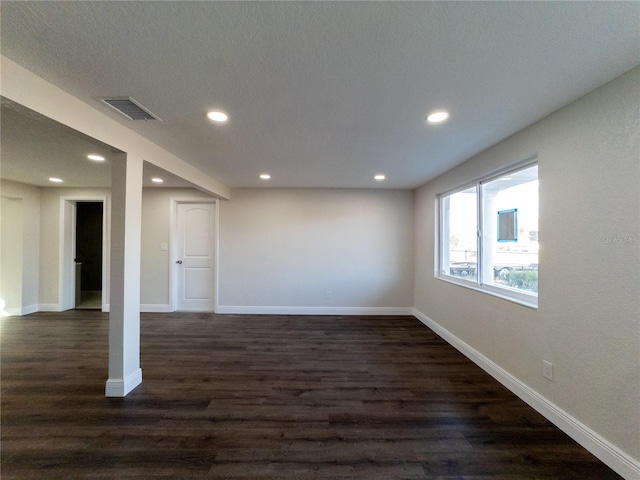 spare room featuring a textured ceiling and dark wood-type flooring