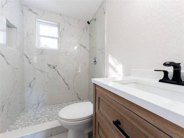 bathroom featuring tiled shower, vanity, and toilet