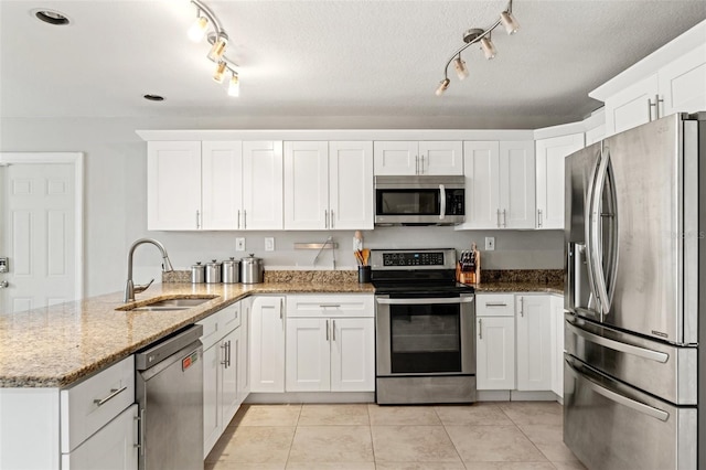 kitchen featuring stainless steel appliances, white cabinets, light stone countertops, and kitchen peninsula