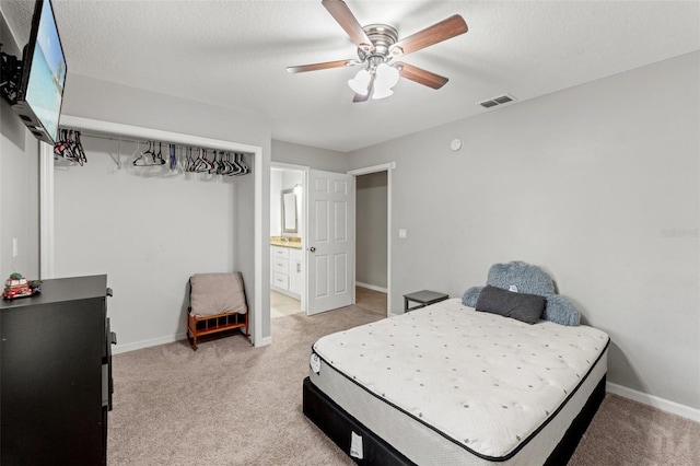 carpeted bedroom with a textured ceiling, ceiling fan, and connected bathroom