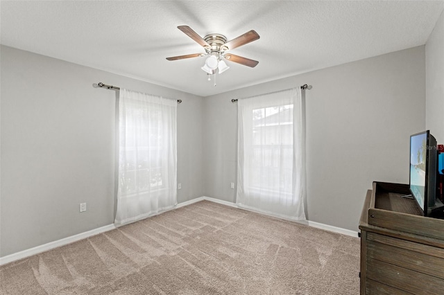 carpeted bedroom featuring multiple windows, a textured ceiling, and ceiling fan