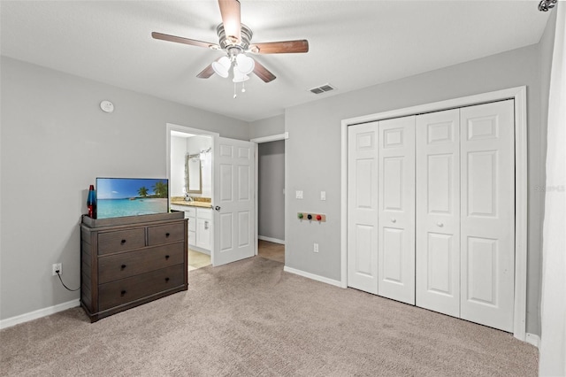 carpeted bedroom featuring ceiling fan, a closet, and ensuite bath