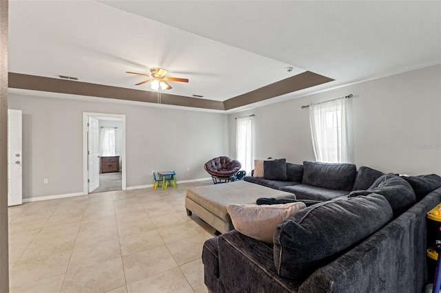 tiled living room featuring ceiling fan and a raised ceiling