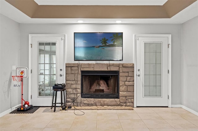 living room featuring a raised ceiling, light tile patterned floors, and a stone fireplace