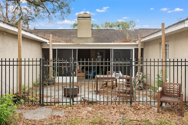 rear view of house with a fire pit and a sunroom