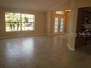 tiled spare room with lofted ceiling and baseboards