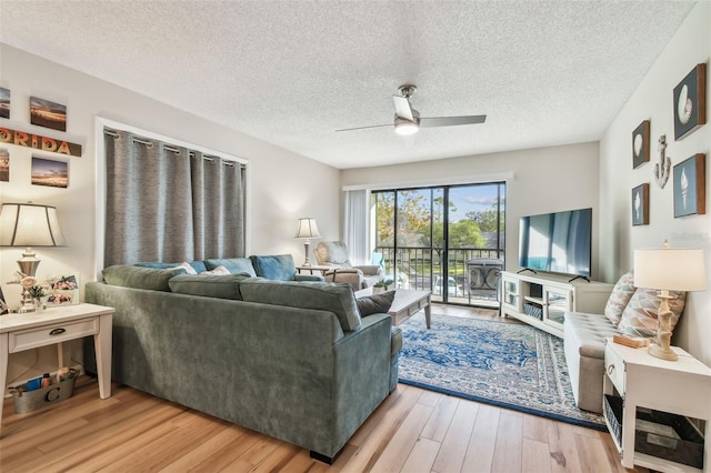 living room with ceiling fan, light hardwood / wood-style floors, and a textured ceiling