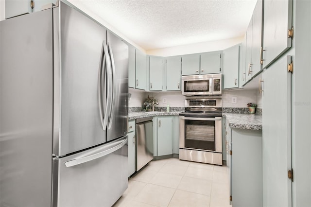 kitchen with appliances with stainless steel finishes, a textured ceiling, and light tile patterned floors