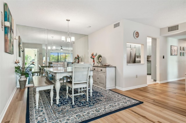 dining area with a notable chandelier and light hardwood / wood-style floors