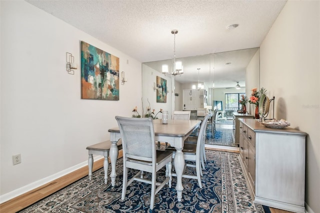 dining space with a textured ceiling, ceiling fan with notable chandelier, and hardwood / wood-style flooring