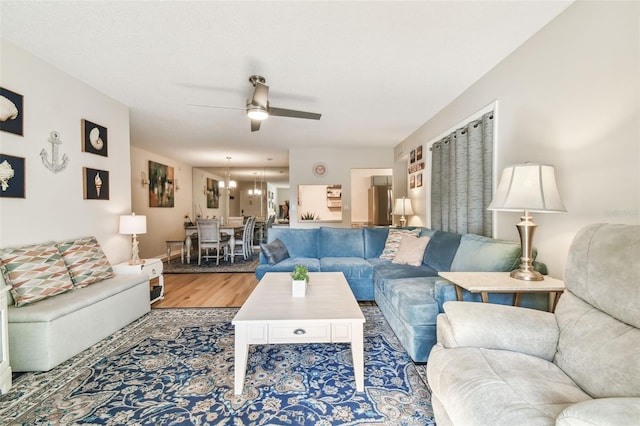 living room with wood-type flooring and ceiling fan with notable chandelier