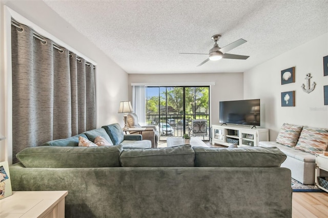 living room with ceiling fan, light hardwood / wood-style floors, and a textured ceiling