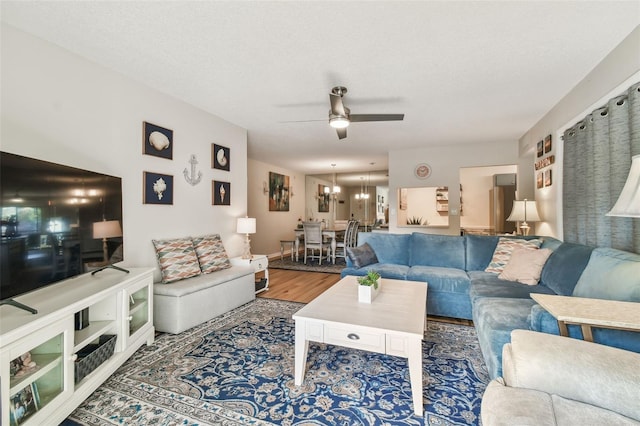 living room featuring hardwood / wood-style floors, ceiling fan with notable chandelier, and a textured ceiling