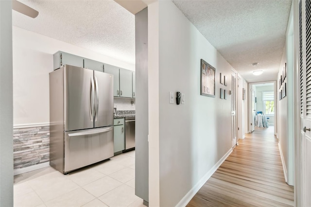 hallway with light hardwood / wood-style floors and a textured ceiling