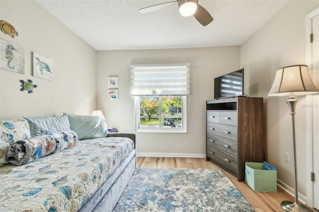 bedroom with ceiling fan, light hardwood / wood-style floors, and a textured ceiling