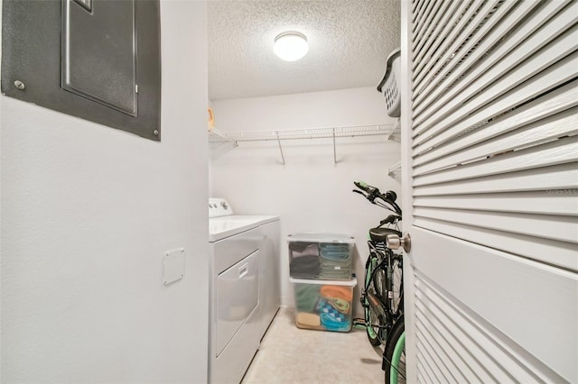 laundry room featuring washing machine and dryer, electric panel, and a textured ceiling