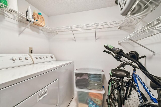 clothes washing area with washing machine and clothes dryer and a textured ceiling