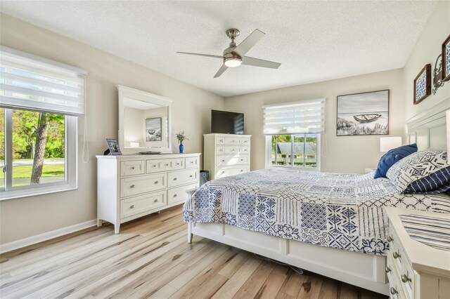 bedroom featuring multiple windows, ceiling fan, light hardwood / wood-style floors, and a textured ceiling