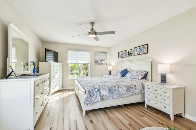 bedroom with ceiling fan, a textured ceiling, and light wood-type flooring