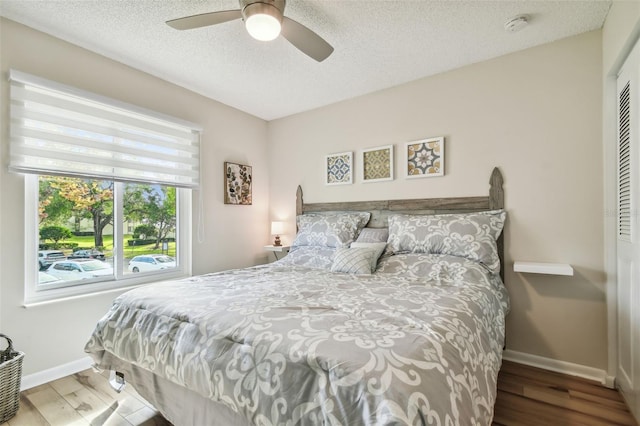 bedroom with wood-type flooring, a textured ceiling, a closet, and ceiling fan