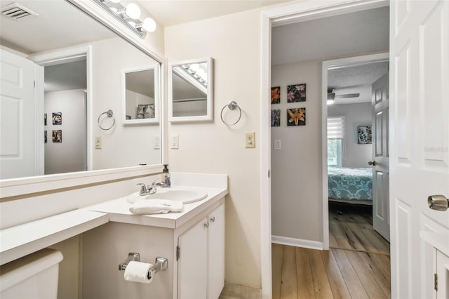 bathroom with ceiling fan, vanity, wood-type flooring, and toilet