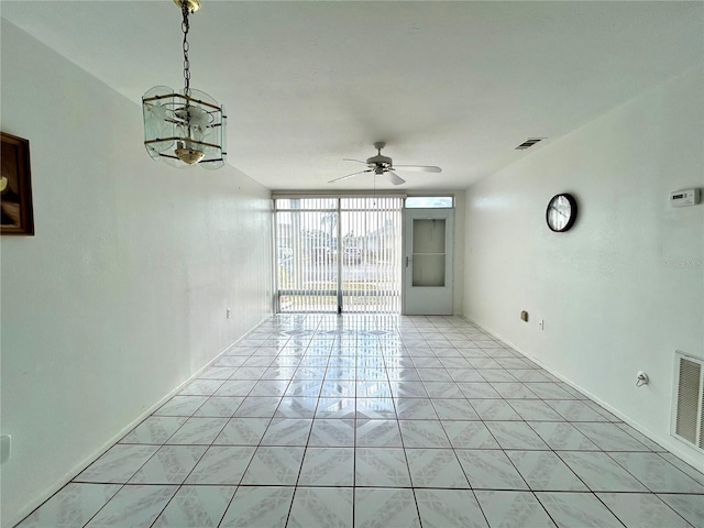 unfurnished room featuring ceiling fan, a wall of windows, and light tile patterned floors