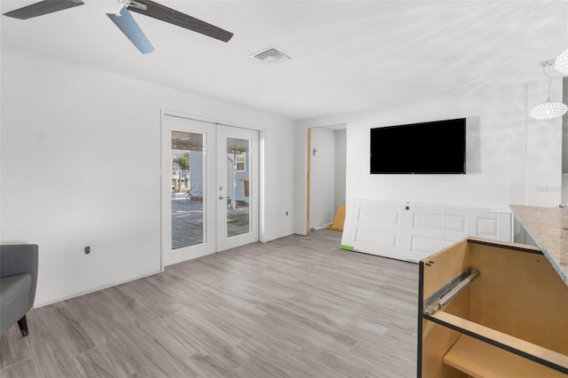 unfurnished living room featuring ceiling fan, french doors, and light hardwood / wood-style flooring