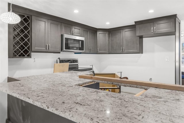 kitchen featuring pendant lighting, dark brown cabinets, light stone countertops, and stainless steel appliances