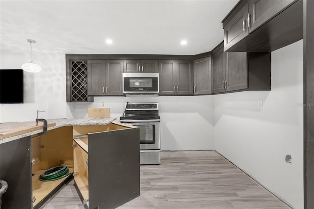 kitchen with hanging light fixtures, light stone countertops, light hardwood / wood-style floors, dark brown cabinetry, and stainless steel appliances