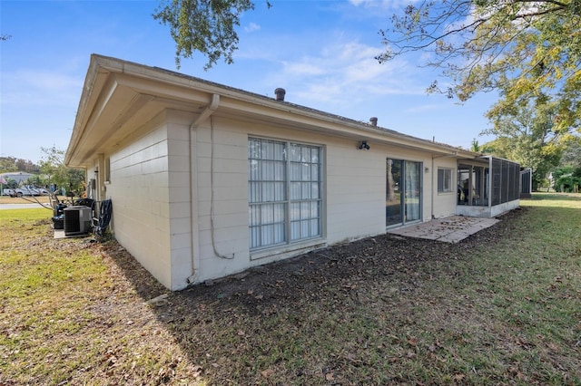 view of side of home featuring a yard, a sunroom, and central air condition unit