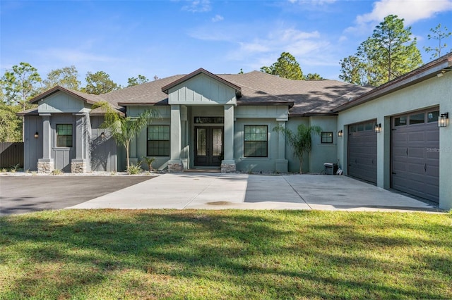 view of front of home featuring french doors, a garage, and a front lawn