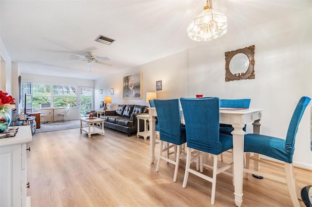 dining area featuring a textured ceiling, light hardwood / wood-style flooring, and ceiling fan with notable chandelier