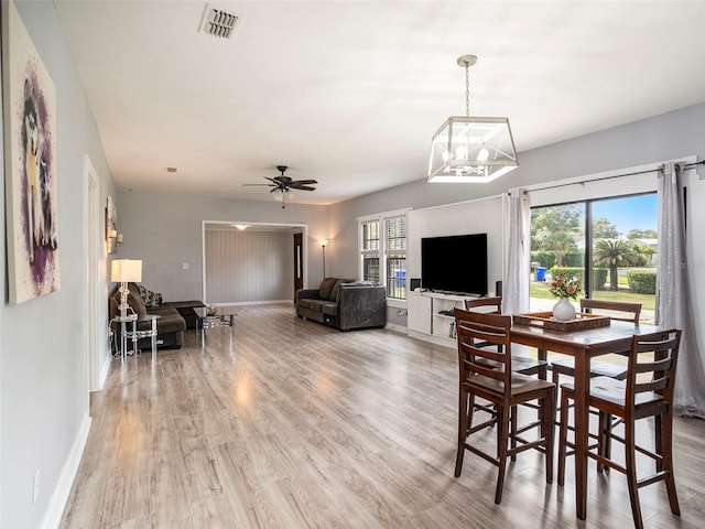 dining area featuring wood-type flooring and ceiling fan with notable chandelier