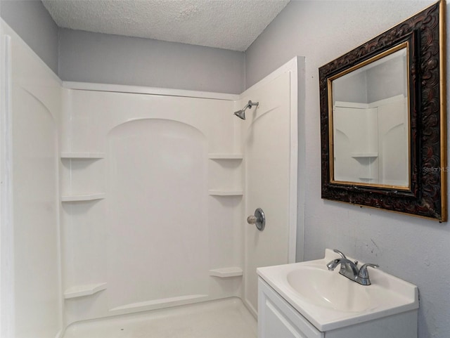 bathroom with vanity, a shower, and a textured ceiling