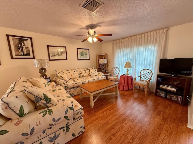 living room featuring hardwood / wood-style floors, ceiling fan, and a textured ceiling