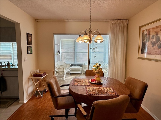 dining space with light wood-type flooring, a wealth of natural light, and an inviting chandelier