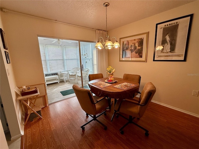 dining area with ceiling fan with notable chandelier, wood-type flooring, and a textured ceiling