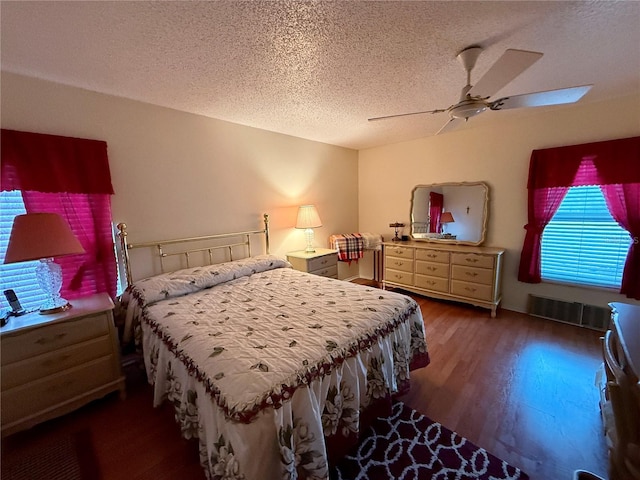 bedroom with a textured ceiling, ceiling fan, and dark wood-type flooring