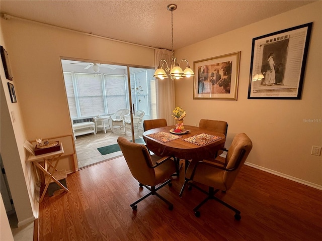 dining area featuring baseboards, an inviting chandelier, wood finished floors, and a textured ceiling