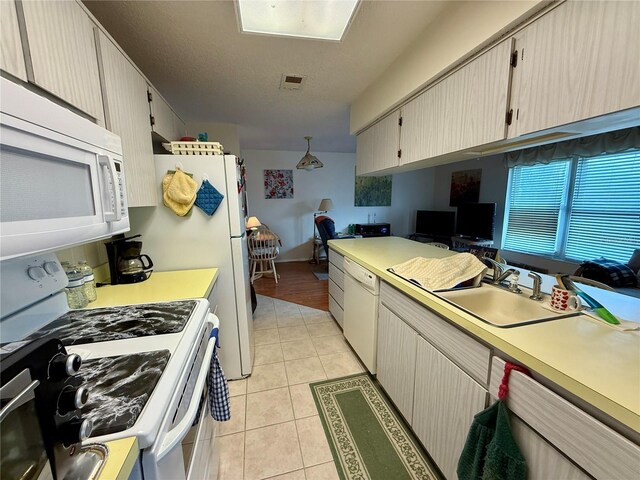 kitchen featuring light countertops, white appliances, light tile patterned floors, a sink, and visible vents