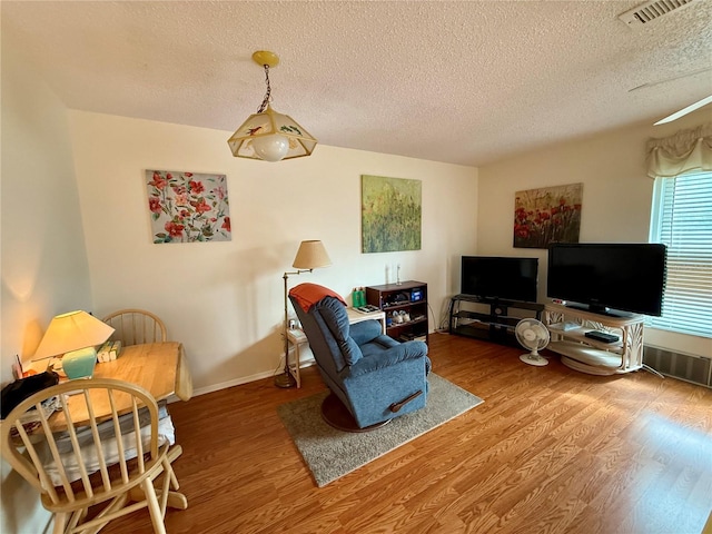 living area with visible vents, wood finished floors, and a textured ceiling