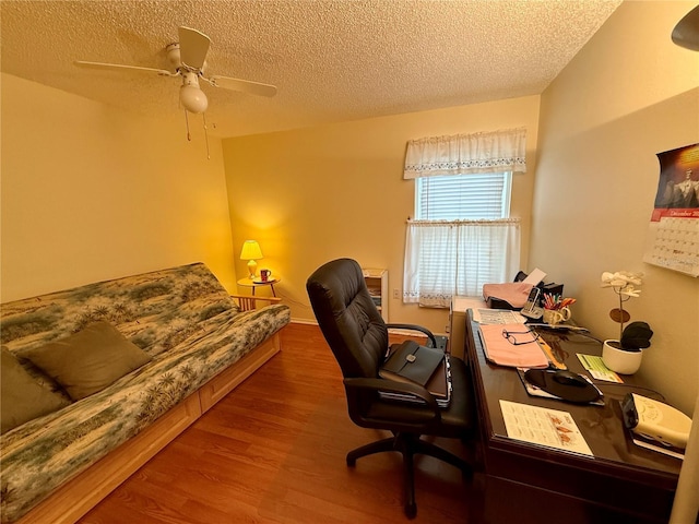 office area featuring baseboards, wood finished floors, ceiling fan, and a textured ceiling