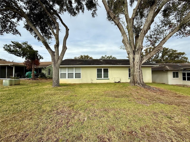 back of property with a lawn and stucco siding