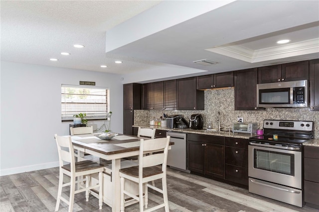 kitchen with appliances with stainless steel finishes, light wood-type flooring, crown molding, and sink