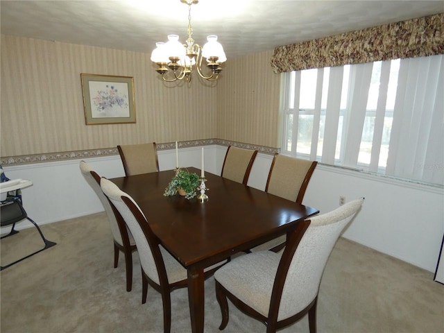 carpeted dining area with a chandelier